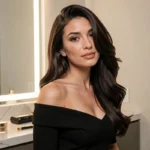Femme aux cheveux bruns lissés et volumineux avec du gel en poudre, en robe noire élégante devant un miroir de coiffeuse
