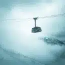 grey cable car traveling above snow covered mountain