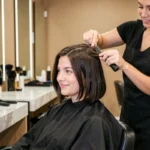 Femme en salon de coiffure lors d'une transition de cheveux longs vers un carré, coiffeuse en action avec ciseaux professionnels